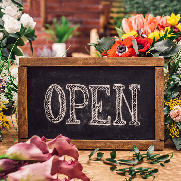 Open sign on table with flowers